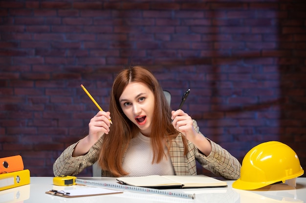 Vorderansicht Arbeiterin auf der Baustelle, die hinter dem Tisch sitzt, notiert Agenda Job Engineer Plan Corporate