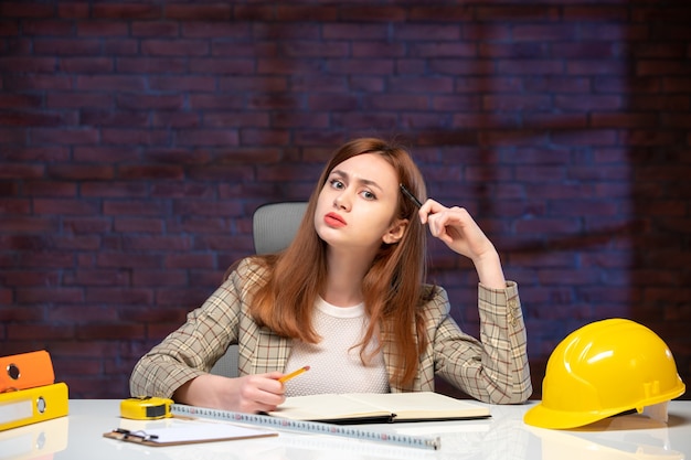 Vorderansicht Arbeiterin auf der Baustelle sitzt hinter Tisch Agenda Job Engineer Business Manager Corporate Plan