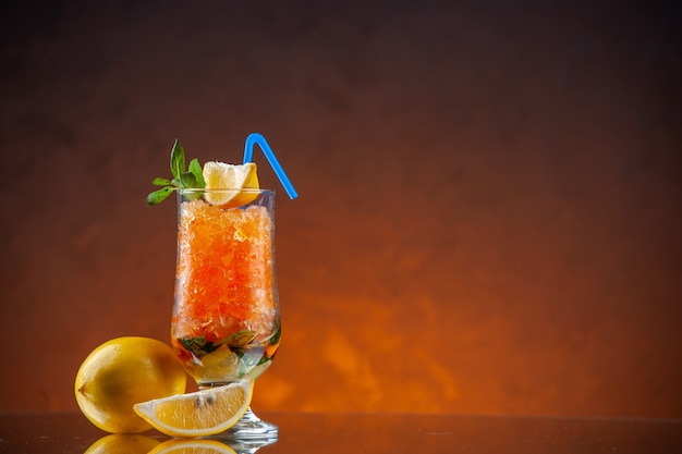 Vorderansicht cooler Orangencocktail mit Zitrone und Eis auf orangefarbenem Hintergrund eiskaltes Getränk Farbe Limonade Bar Saft freier Raum