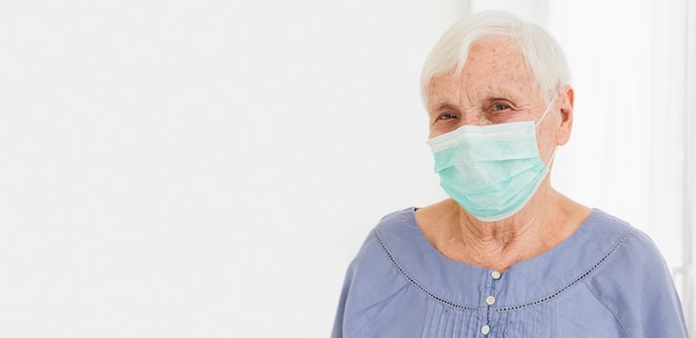 Vorderansicht der älteren Frau mit medizinischer Maske und Kopienraum