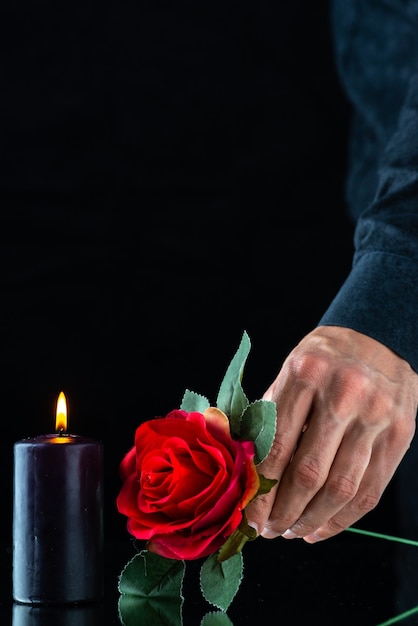 Vorderansicht der dunklen Kerze mit roter Rose auf der dunklen Oberfläche