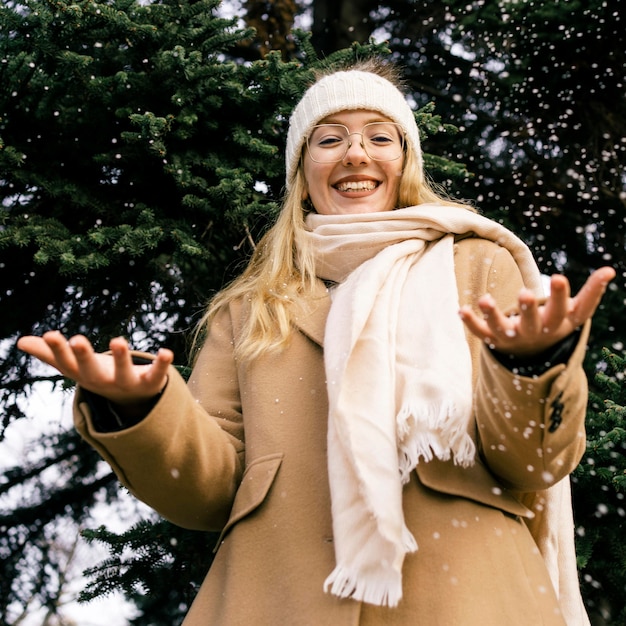 Vorderansicht der Frau, die mit Schnee am Park im Winter spielt