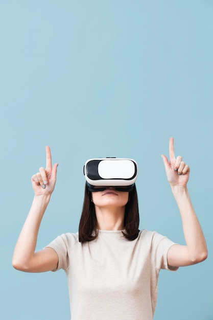 Vorderansicht der Frau, die Virtual-Reality-Headset trägt und nach oben zeigt