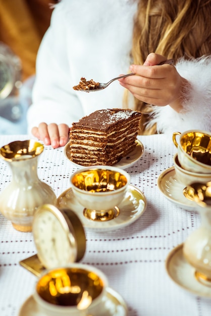 Vorderansicht der Hände des kleinen schönen Mädchens, die ein Stück Kuchen auf einem Löffel im Park halten