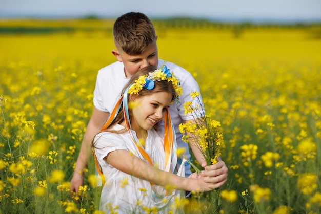 Vorderansicht der Kinder Bruder und Schwester, die weit weg auf einem Weg mit Gras gehen, umgeben von gelben Feldern