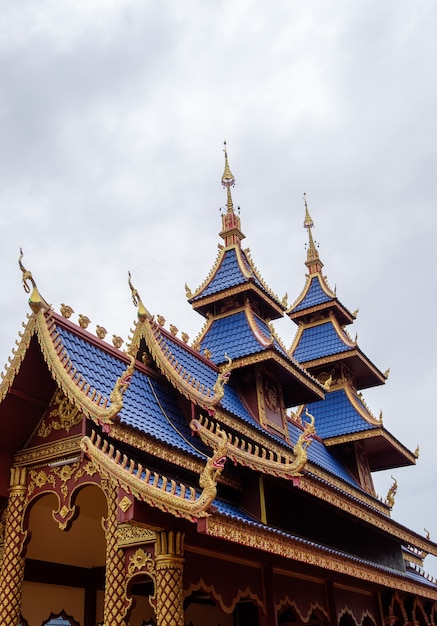 Vorderansicht des Eingangs zur thailändischen Kirche im thailändischen Tempel, blaue Dachziegel kontrastieren mit goldenen Gebäuden, Vorderansicht für den Kopierraum.