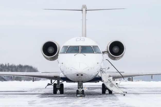 Vorderansicht des Executive-Flugzeugs mit geöffneter Gangway-Tür auf dem Vorfeld des Winterflughafens