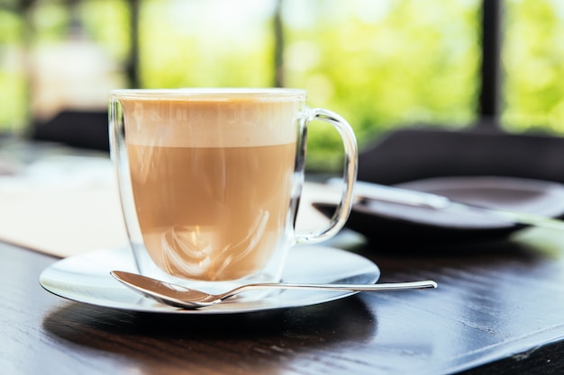 Vorderansicht des heißen schaumigen Cappucino mit Unschärfegrünhintergrund.