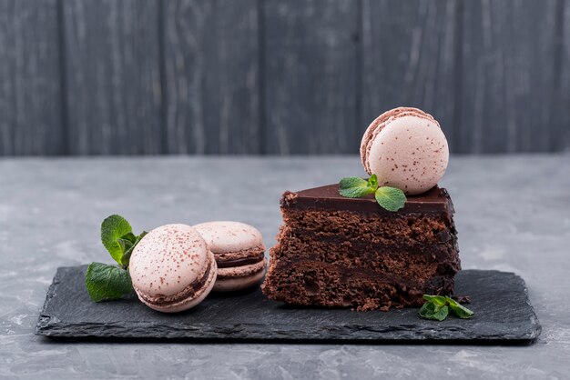 Foto vorderansicht des kuchens auf schiefer mit minze und macarons