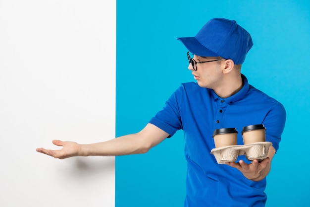 Vorderansicht des männlichen Kuriers in Uniform mit Lieferkaffee auf Blau