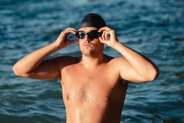 Foto vorderansicht des männlichen schwimmers mit schwimmbrille und mütze