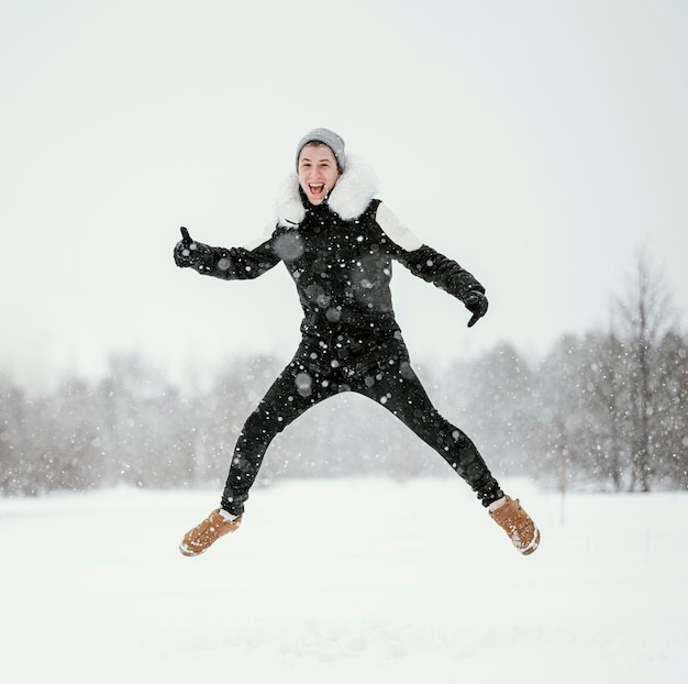 Vorderansicht des Mannes, der in der Luft draußen im Winter springt