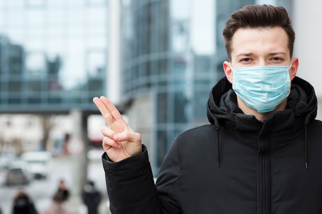 Vorderansicht des Mannes mit Coronavirus, der medizinische Maske in der Stadt trägt