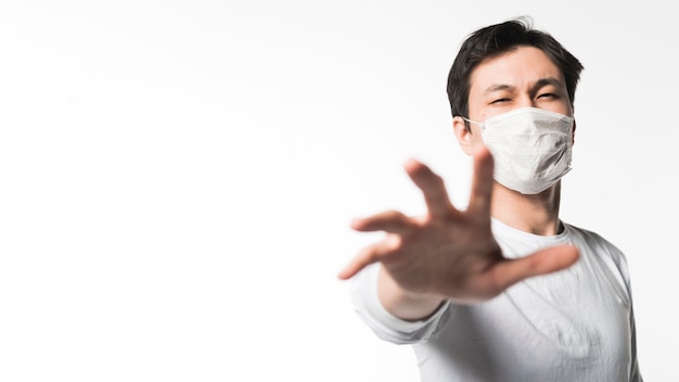 Foto vorderansicht des mannes mit der medizinischen maske, die nach etwas greift