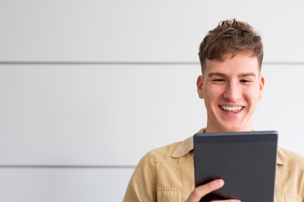 Foto vorderansicht des smiley-mannes, der tablette mit kopienraum betrachtet