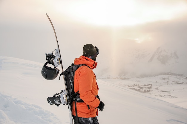 Vorderansicht des Snowboarders schauend auf Bergspitzen