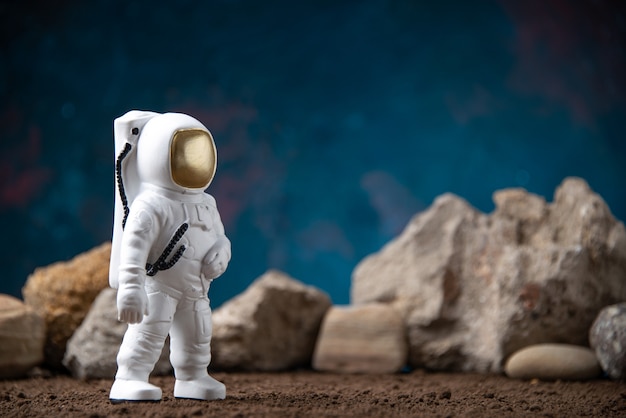 Vorderansicht des weißen Astronauten mit Felsen auf mondblauer kosmischer Science-Fiction-Fantasie