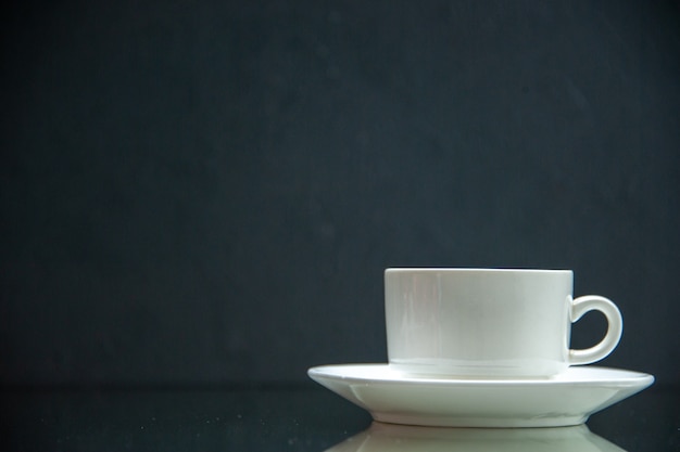 Foto vorderansicht des weißen sets aus kaffeetasse und untertasse auf der linken seite auf dunklem wellenhintergrund mit freiem platz