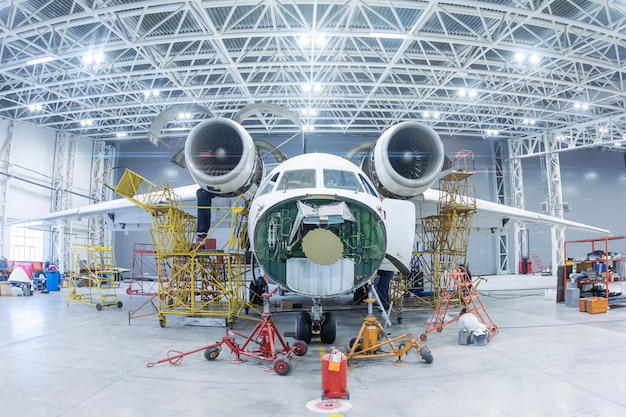 Vorderansicht des weißen Transportflugzeugs im Hangar Flugzeuge in Wartung