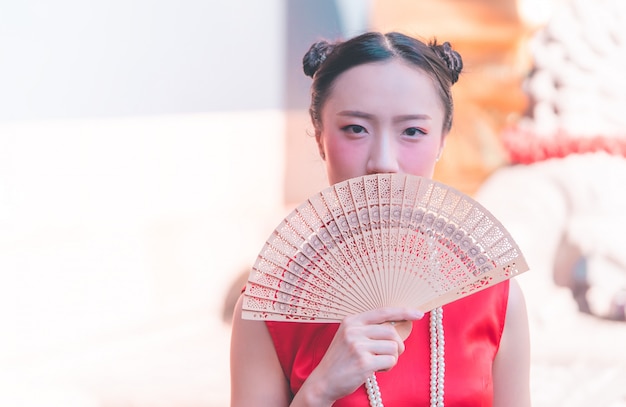 Vorderansicht einer chinesischen frau mit hölzernem fan im tempel