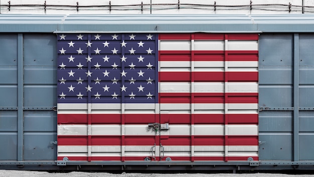 Vorderansicht eines containerzuggüterwagens mit einem großen metallverschluß mit der staatsflagge von usa das konzept des exportimports, des transportes, der nationalen lieferung von waren und des schienentransports