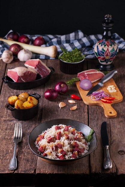 Foto vorderansicht eines tellers, der vom reis mit ruckartigem rindfleisch auf einem rustikalen hölzernen tischküchenbrett mit ruckartigen roten zwiebelknoblauchpfefferstücken und einem küchenmesser gedient wird dunkler hintergrund mit kopienraum