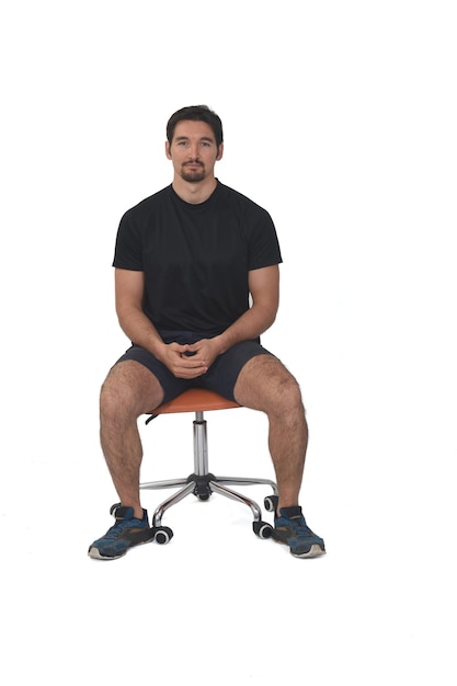 Vorderansicht eines vollständigen Porträts eines Mannes, der auf einem Stuhl sitzt und in Sportkleidung auf weißem Hintergrund in die Kamera blickt