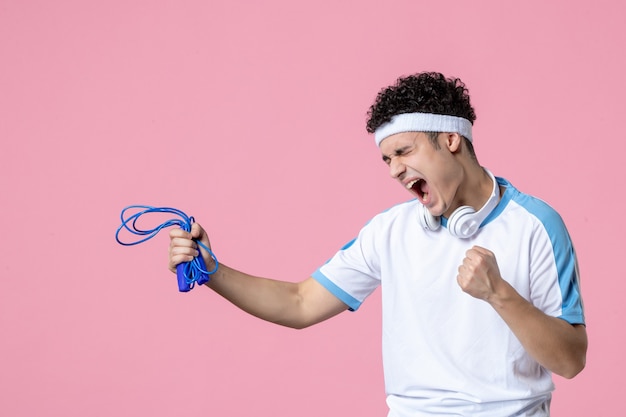 Vorderansicht emotionaler junger Mann in Sportkleidung mit Springseil