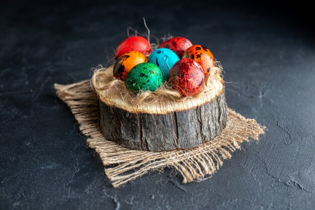 Vorderansicht farbige Ostereier auf Holzstück dunkler Hintergrund Ostern Farbe ethnisch verzierte bunte Feiertage