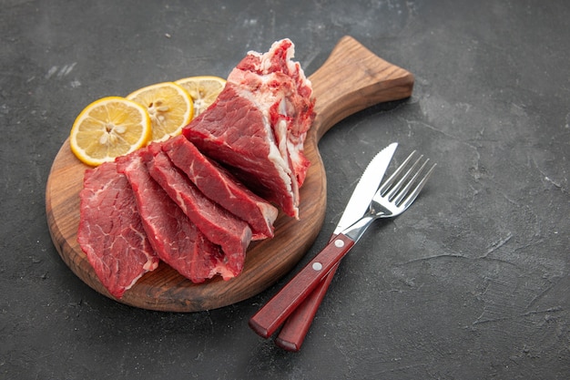 Vorderansicht frisch geschnittenes Fleisch mit Zitronenscheiben auf dunklem Hintergrund Tierfutter Grill Metzger Fleisch Abendessen Essen kochen