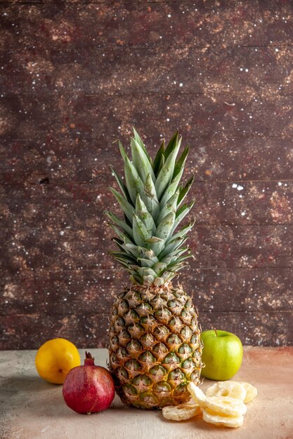 Vorderansicht frische Ananas trockene Ananasscheiben Apfel Granatapfel Zitrone auf braunem Hintergrund