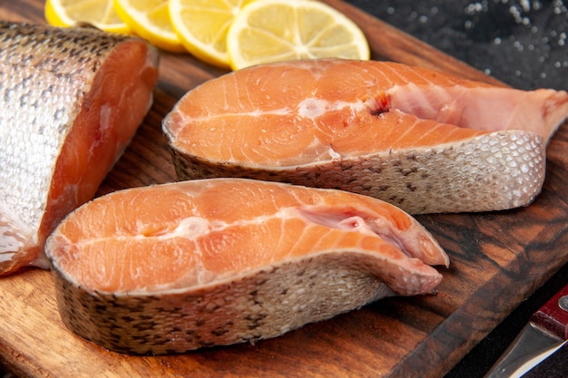 Vorderansicht frische Fischscheiben mit Zitronenscheiben auf dunklem Hintergrund Mahlzeit Salat Meeresfrüchte Wasser Fisch Fleisch Meer Ozean Essen