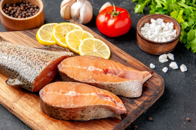 Vorderansicht frischer Fisch mit Grün und Zitrone auf dunklem Hintergrund Fischsalat Wasser Fleisch Ozean Meer Mahlzeit Abendessen Meeresfrüchte