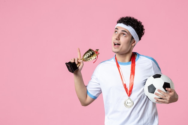 Vorderansicht Fußballspieler in Sportkleidung mit goldenem Pokal und Medaille
