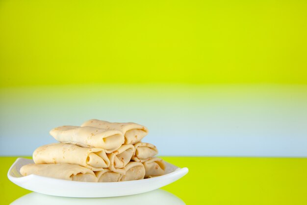 Vorderansicht gerollte süße Pfannkuchen in der Platte auf gelbem Hintergrund Kuchen Morgenessen Frühstück Mahlzeit Zucker Milch Farbe