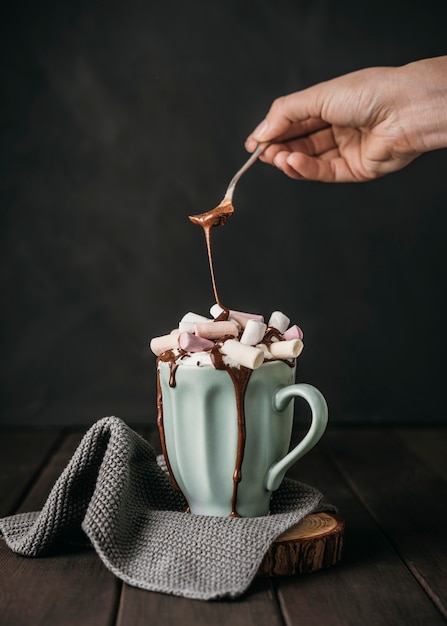 Vorderansicht Hand, die Schokoladensauce über Marshmallows gießt