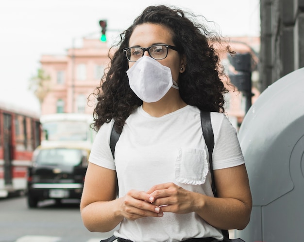 Foto vorderansicht junge frau, die eine medizinische maske draußen trägt