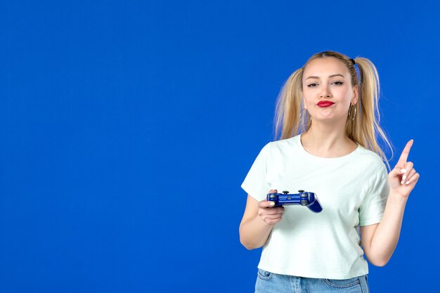 Vorderansicht junge Frau, die Videospiel mit Gamepad auf blauem Hintergrund spielt