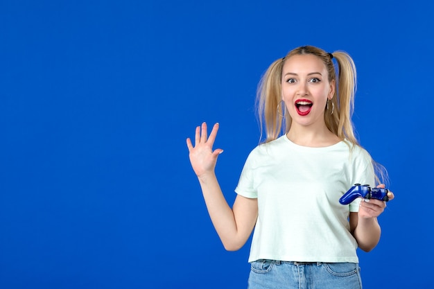 Vorderansicht junge Frau mit Gamepad auf blauem Hintergrund Erwachsener fröhlicher virtueller Spieler Internetvideo Online-Jugendsofa