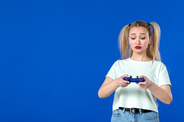 Vorderansicht junge Frau mit Gamepad, die Videospiel auf blauem Hintergrund spielt Erwachsener fröhlicher virtueller Spieler Internet-Gewinnvideo online Jugend