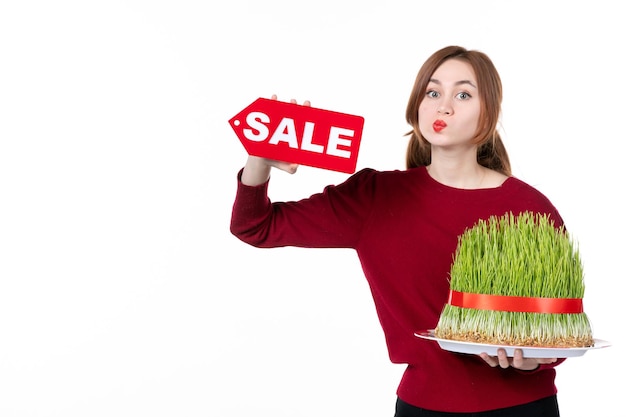 Vorderansicht junge Frau mit großen Novruz Semeni und Verkauf Typenschild auf weißem Hintergrund Konzept Ethnizität Familie Shopping Performer Farben Frühling