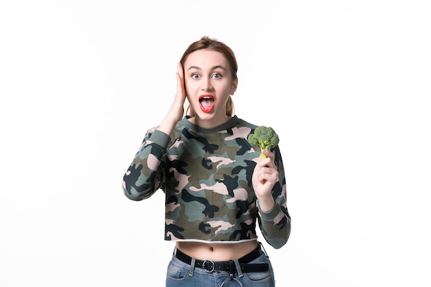 Vorderansicht junge Frau mit grünem Brokkoli auf weißem Hintergrund Körperdiät horizontale Mahlzeit Mittagessen Gericht Salat Essen