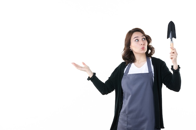 Vorderansicht junge Frau mit Spachtel auf dem weißen Hintergrund Frau Garten grüne Uniform Emotion Baum Boden Natur Blume