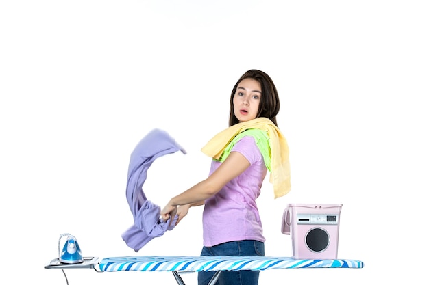 Vorderansicht junge Hausfrau faltende Kleidung zum Bügeln auf weißem Hintergrund Hausarbeit chemische Reinigung Frau Wäsche Emotion Farbe Eisen