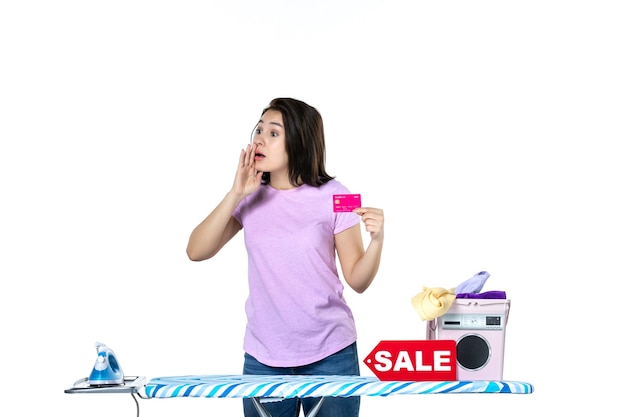 Vorderansicht junge Hausfrau mit rosa Bankkarte auf weißem Hintergrund Einkaufen Wäsche Kleidung Verkauf Eisen Geld Arbeit Farbe