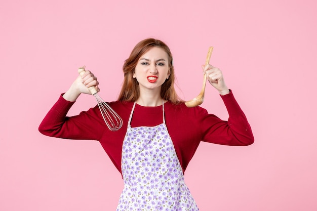 Vorderansicht junge Hausfrau mit Schneebesen und Holzlöffel auf rosa Hintergrund kochen einheitliche Beruf Kuchen Küche Kuchen Frau