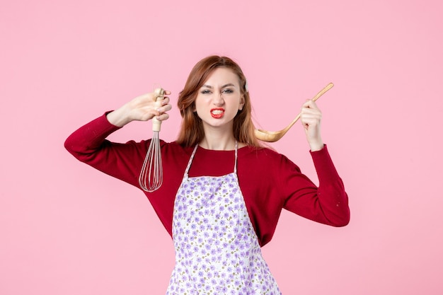 Vorderansicht junge Hausfrau mit Schneebesen und Holzlöffel auf rosa Hintergrund kochen einheitliche horizontale Kuchen Küche Beruf Frau