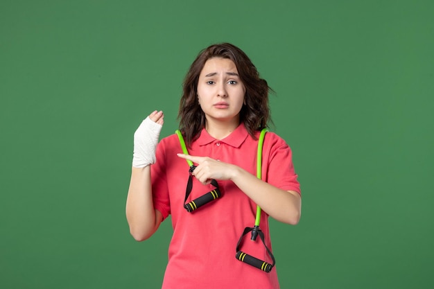 Vorderansicht junge Verkäuferin mit Verband an ihrer verletzten Hand auf grünem Hintergrund Job Farbverletzung Gesundheit Krankenhaus Arbeitsuniform