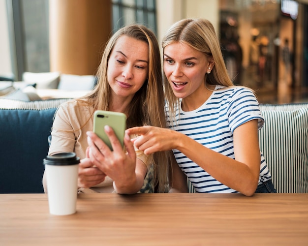 Foto vorderansicht junger frauen, die handy durchsuchen