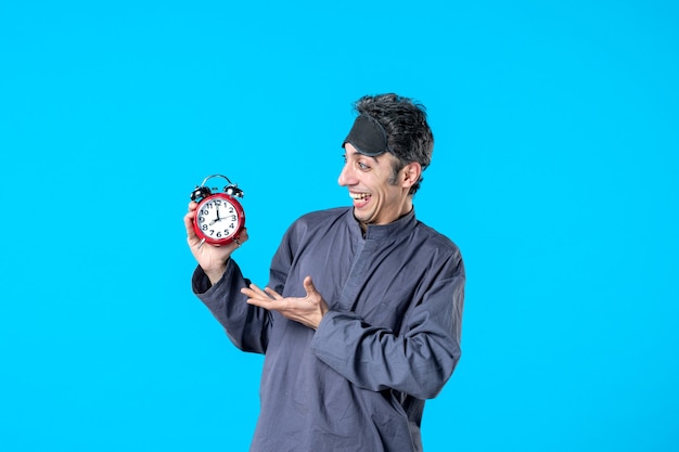 Vorderansicht junger Mann im Pyjama mit roten Uhren auf blauem Hintergrund dunkler Albtraum Schlaflosigkeit schlafen spät träumen Nacht Bettzeit Farben time
